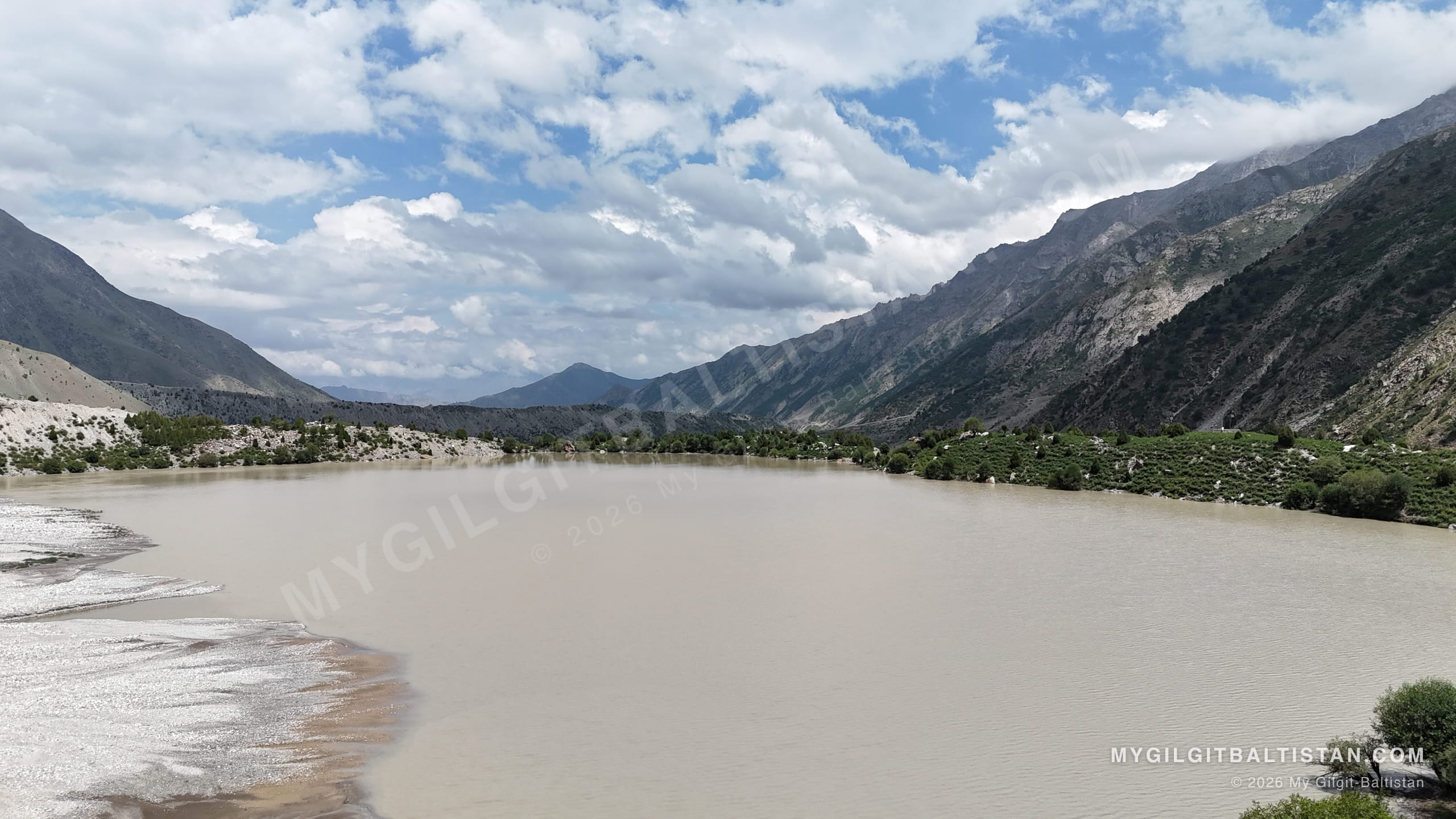 Silt-heavy meltwater spreading across a wide channel below cultivated slopes on the way into Rupal Valley.